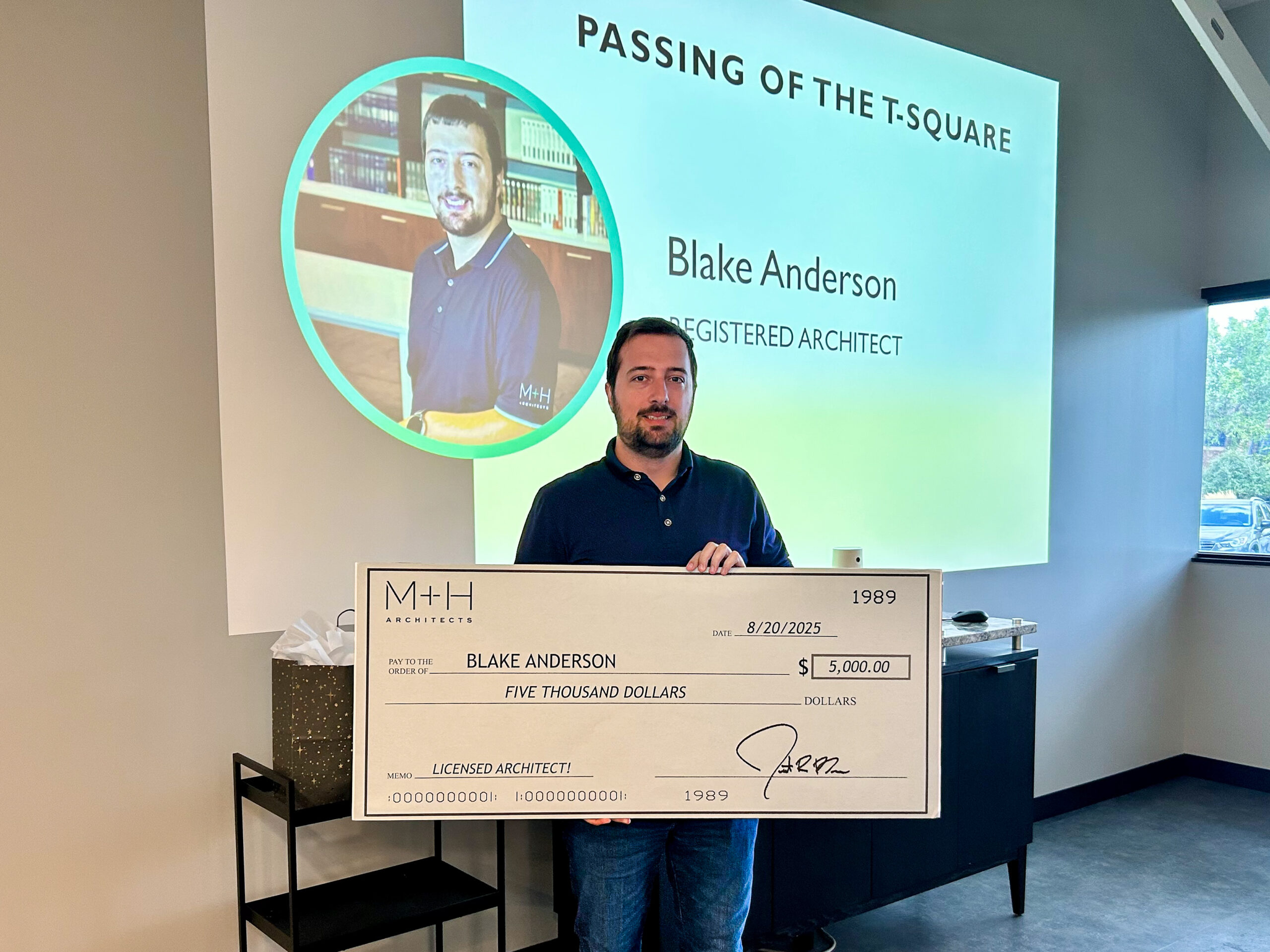 Blake Anderson posing with the oversized check for completing his ARE tests to become a licensed Architect.